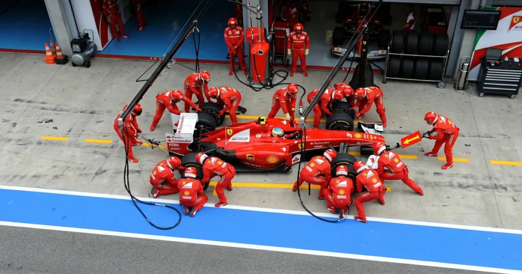Equipe de pit stop da Fórmula 1 trocando os 4 pneus do monoposto em sincronia milimétrica no box