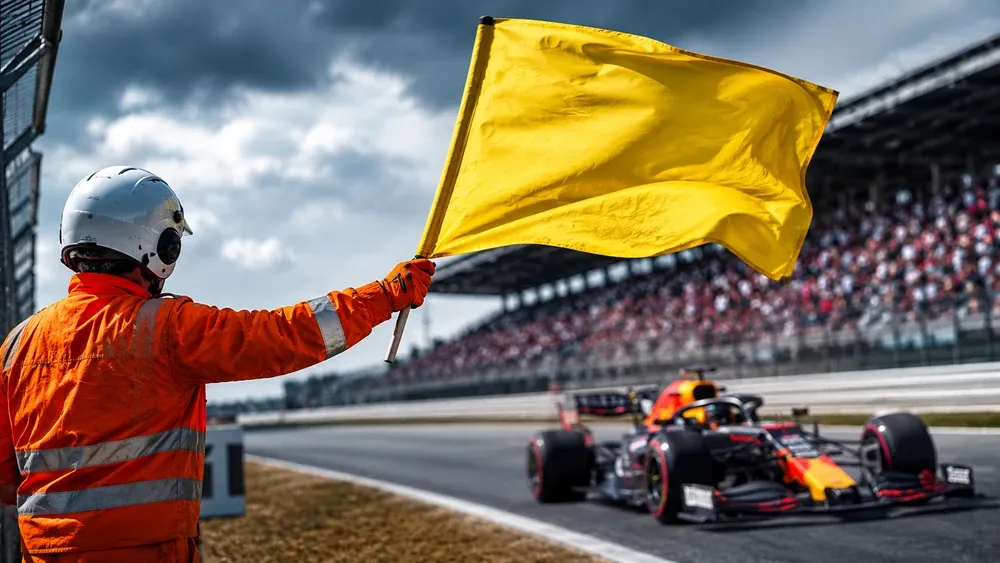 Fiscal de pista acenando a bandeira amarela na beira de um circuito de Fórmula 1 para alertar os pilotos sobre perigo