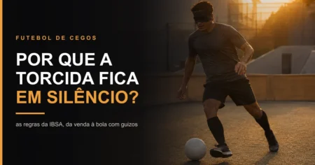Atleta de futebol de cegos com venda nos olhos conduzindo a bola rente ao chão, com barreira lateral ao fundo