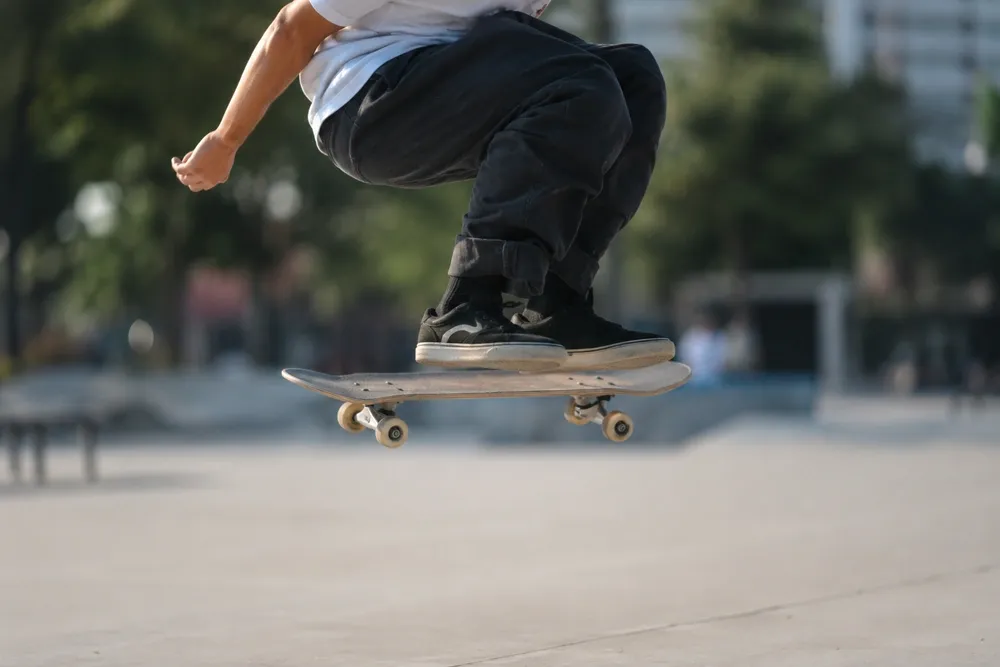 Skatista no ar com o skate nivelado sob os pés durante um ollie em praça urbana